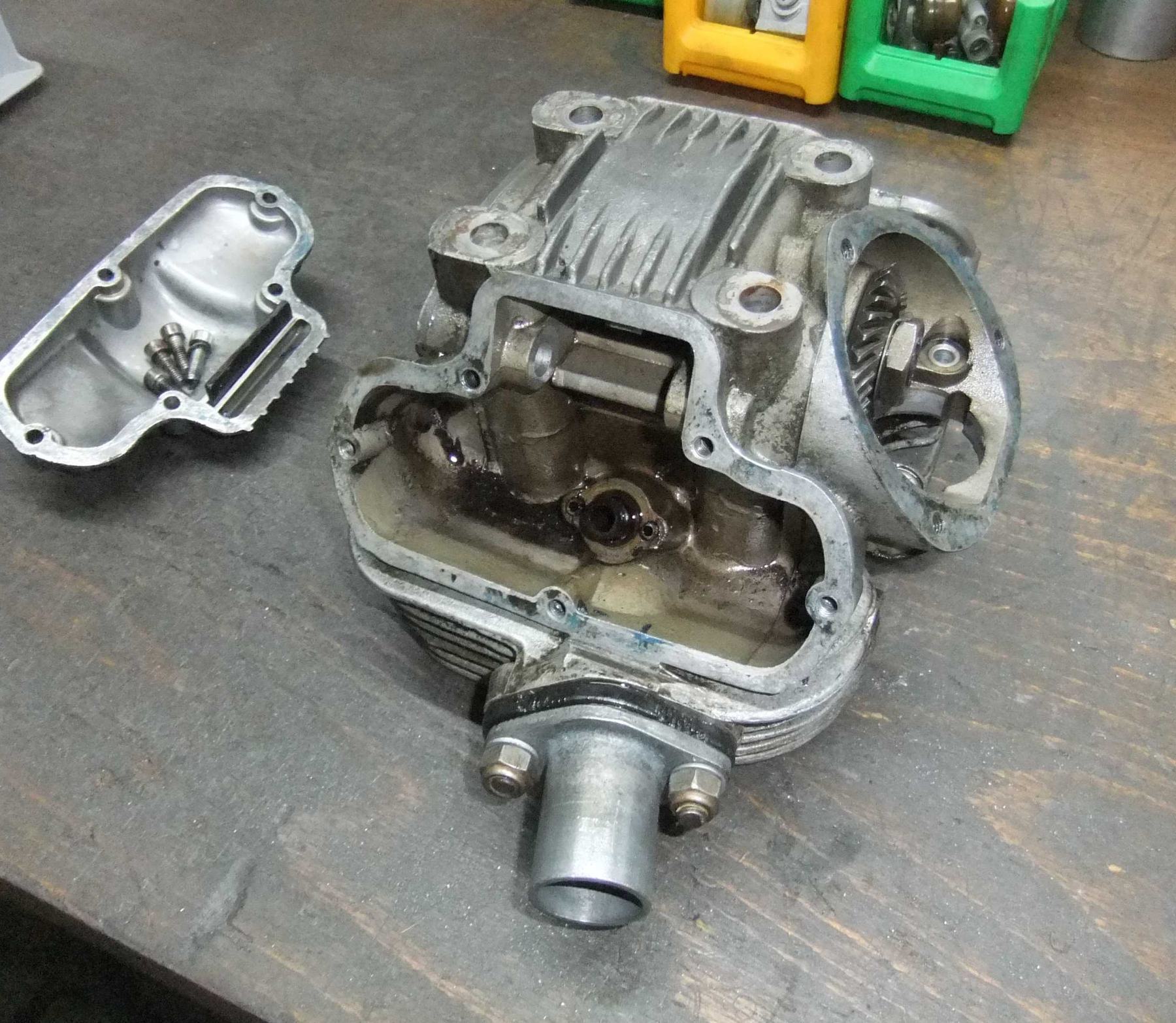 Geöffneter luftgekühlter Ducati-Zylinderkopf auf der Holzwerkbank, daneben der Deckel mit fünf Schrauben