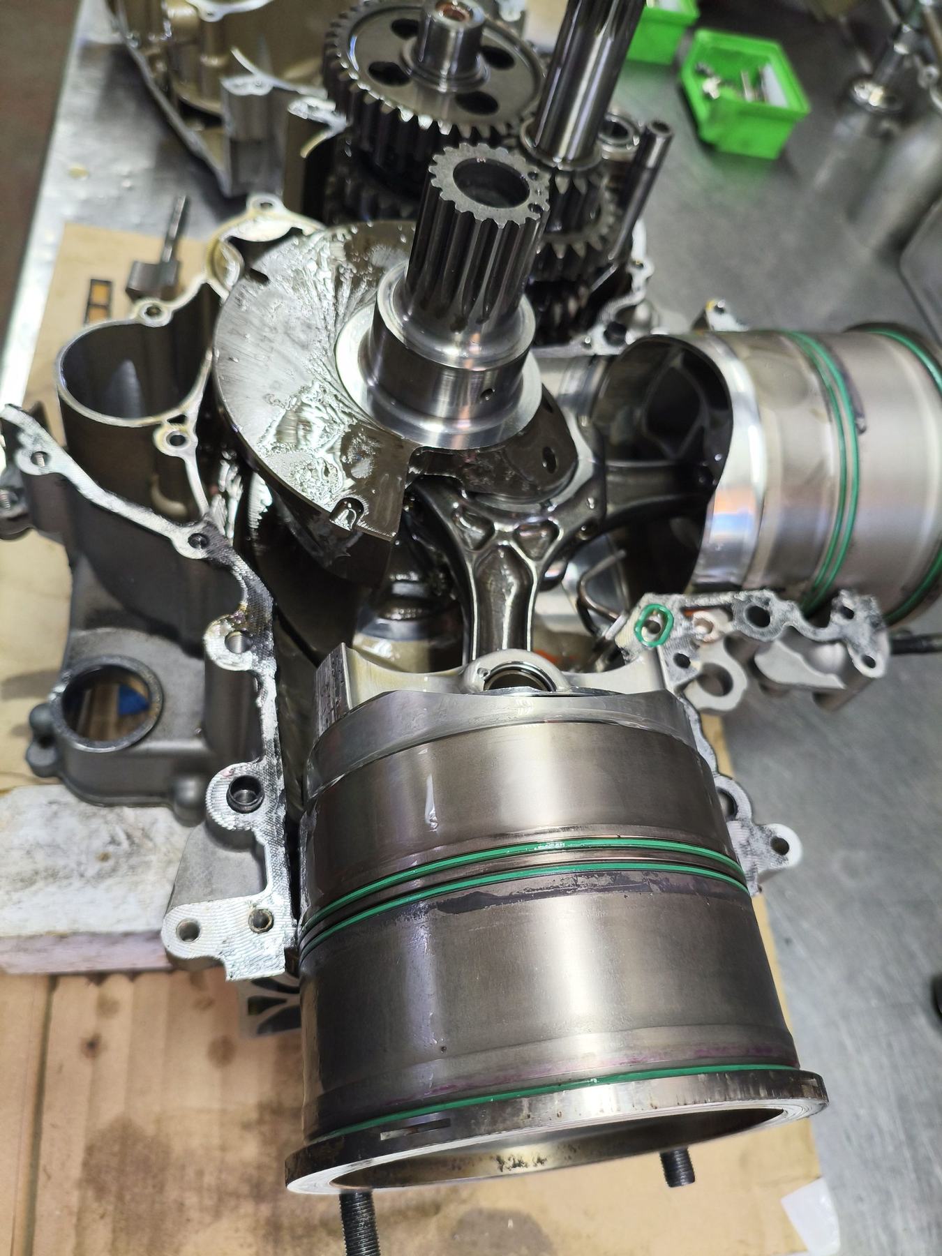 Zerlegter Ducati-V2-Motor auf dem Werktisch: Kurbelwelle, Pleuel und Kolben mit grünen Dichtringen