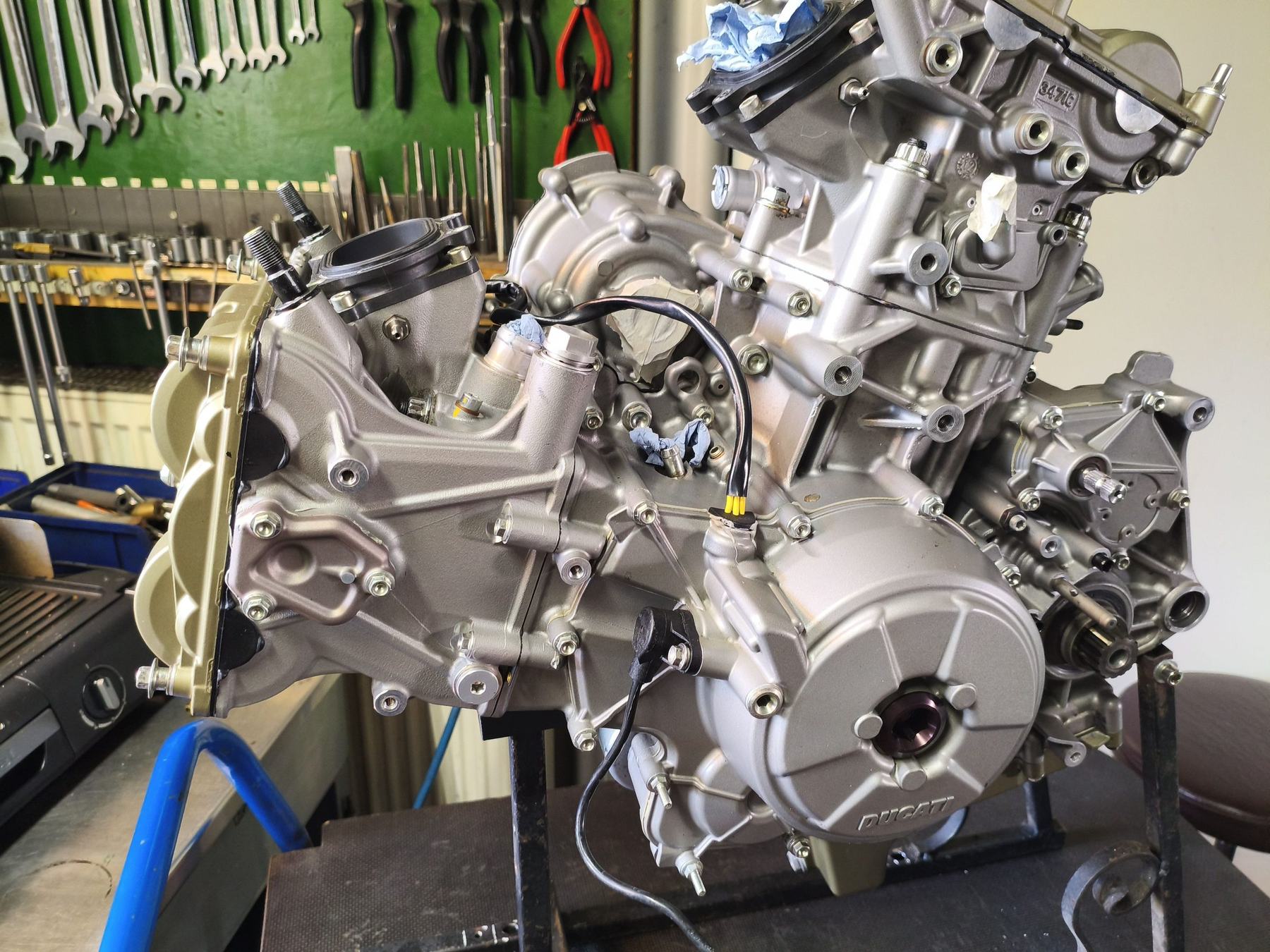 Teilmontierter Ducati-V2-Motor auf dem Montageständer in der Werkstatt, im Hintergrund die Werkzeugwand